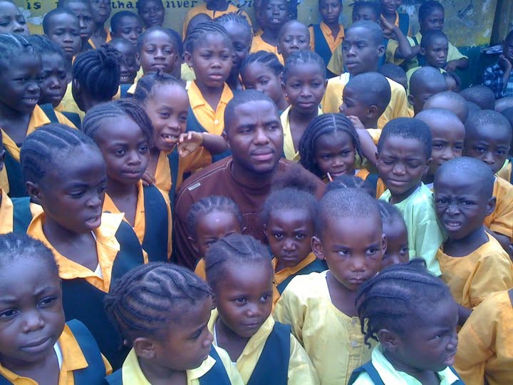 Founder surrounded by smiling schoolchildren in uniform at a partner school